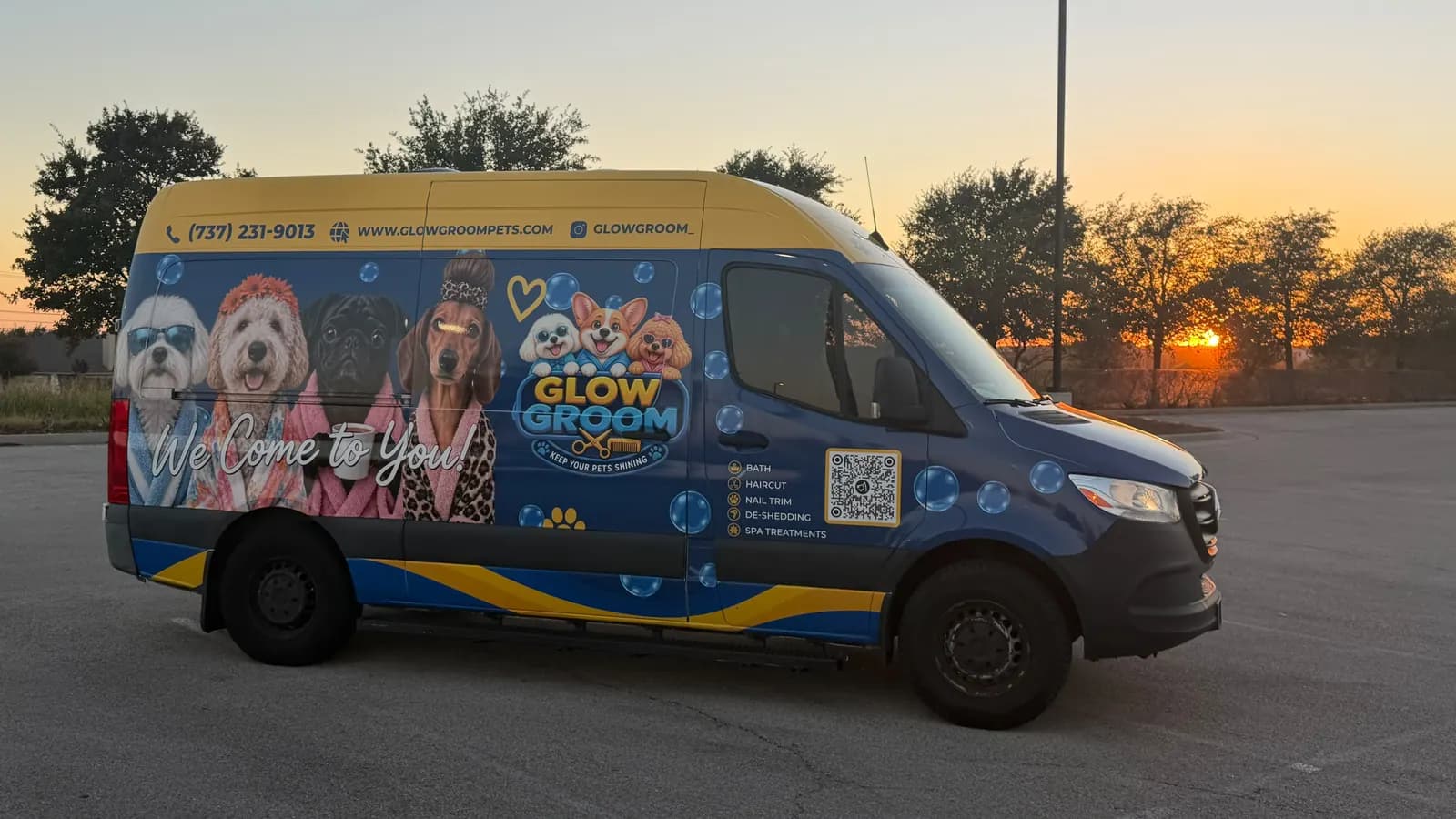 The real Glow Groom mobile grooming van at sunset in the Austin area, wrapped in the blue and gold brand design with the spa dogs, phone number and service list